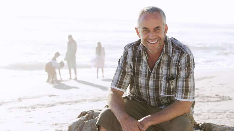 A smiling man with his family on the beach