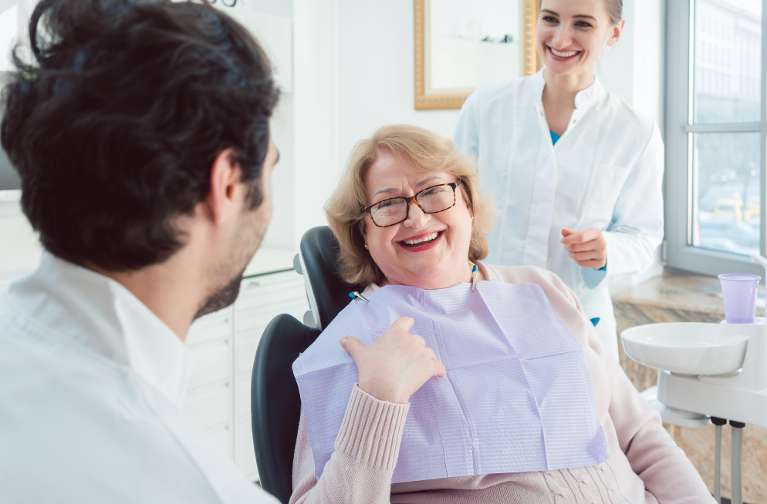 A smiling woman speaking with her dentist