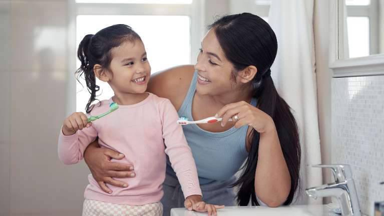 A mother and daughter brushing their teeth