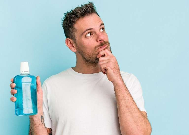 A thinking man holding a bottle of mouthwash