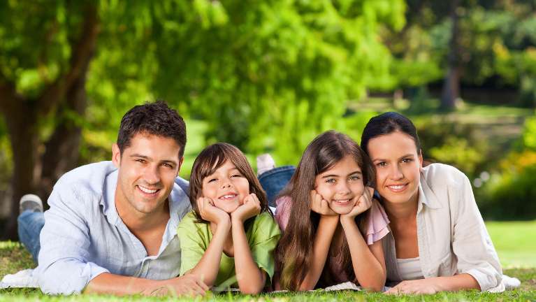 A smiling family in the grass | dentist Kurri Kurri